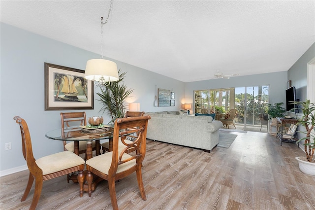 dining area featuring baseboards, light wood-style floors, and a textured ceiling