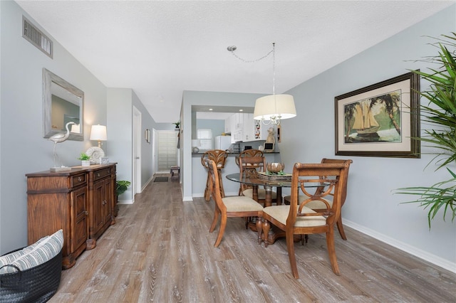 dining room featuring visible vents, a textured ceiling, light wood-type flooring, and baseboards