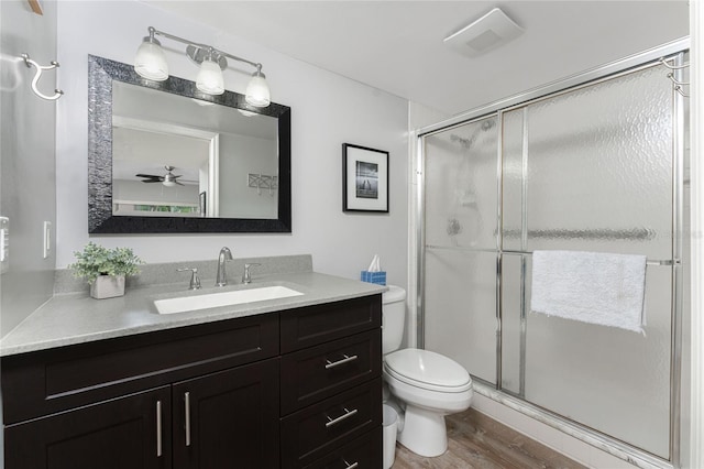 full bathroom with a shower stall, toilet, vanity, and wood finished floors