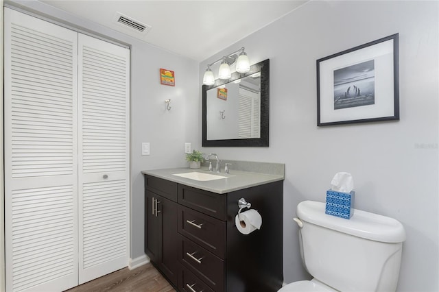 bathroom with vanity, toilet, wood finished floors, and visible vents