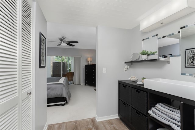 bathroom with baseboards, vanity, ceiling fan, and wood finished floors