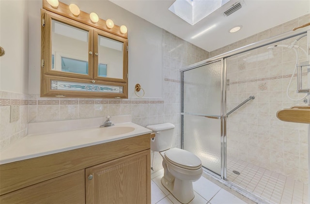 bathroom with tile walls, vanity, a shower with door, and tile patterned floors