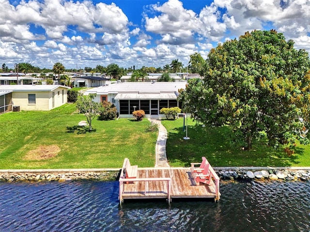 back of house with a water view and a lawn