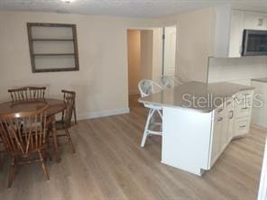 kitchen with built in shelves, a kitchen island, white cabinetry, and light hardwood / wood-style floors