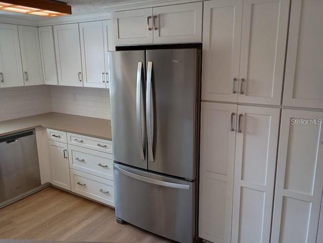 kitchen featuring light wood-type flooring, white cabinets, appliances with stainless steel finishes, and decorative backsplash