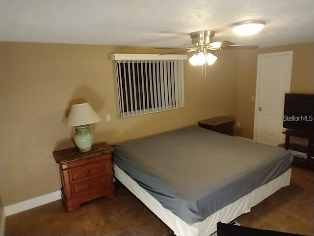 bedroom with ceiling fan and dark tile patterned floors