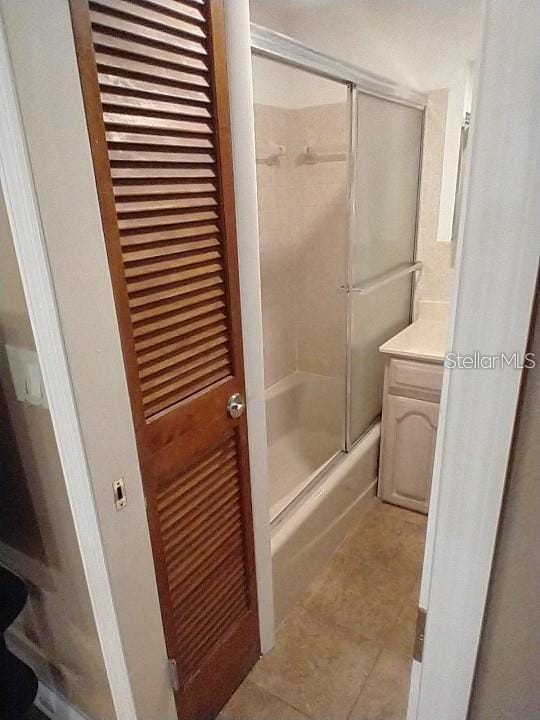 bathroom featuring vanity, tile patterned floors, and bath / shower combo with glass door