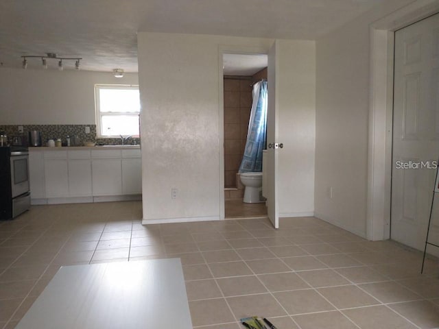 interior space featuring rail lighting, light tile patterned floors, and sink