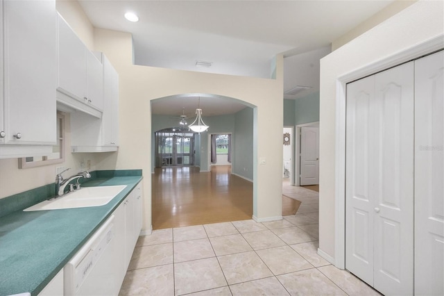 kitchen with light hardwood / wood-style floors, white cabinetry, sink, white dishwasher, and hanging light fixtures