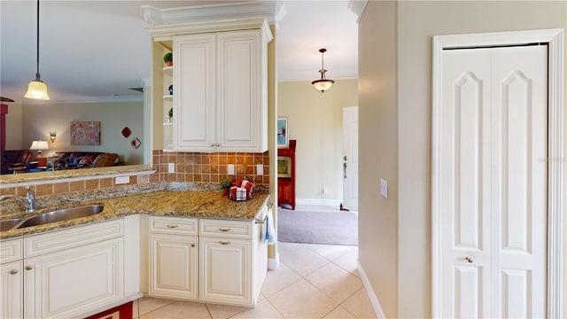 kitchen featuring light stone counters, ornamental molding, a sink, backsplash, and light tile patterned flooring