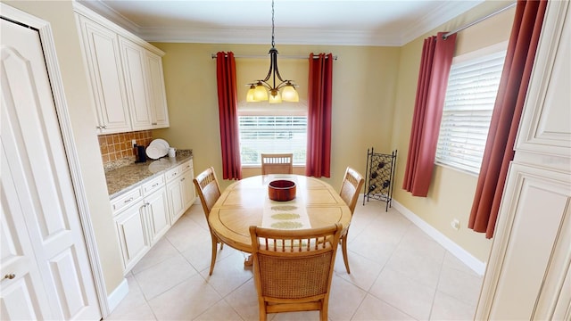 dining space with a notable chandelier, crown molding, baseboards, and light tile patterned floors