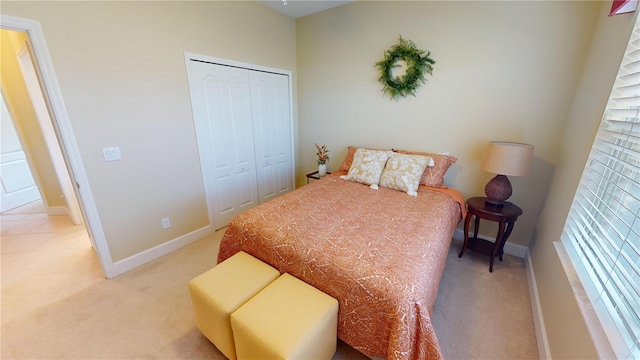 bedroom with a closet, light carpet, and baseboards