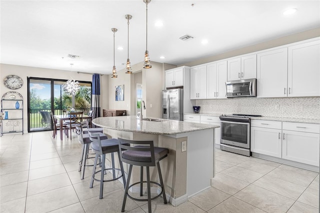 kitchen featuring backsplash, appliances with stainless steel finishes, light stone countertops, white cabinetry, and pendant lighting