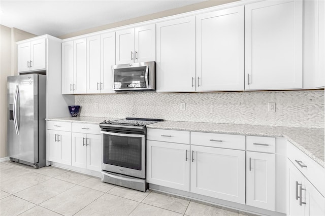 kitchen with tasteful backsplash, white cabinetry, light stone counters, light tile patterned floors, and stainless steel appliances