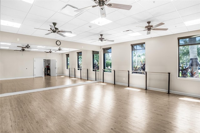 workout area with ceiling fan, a wealth of natural light, and wood-type flooring