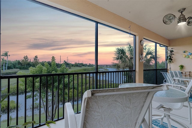 balcony at dusk featuring a water view