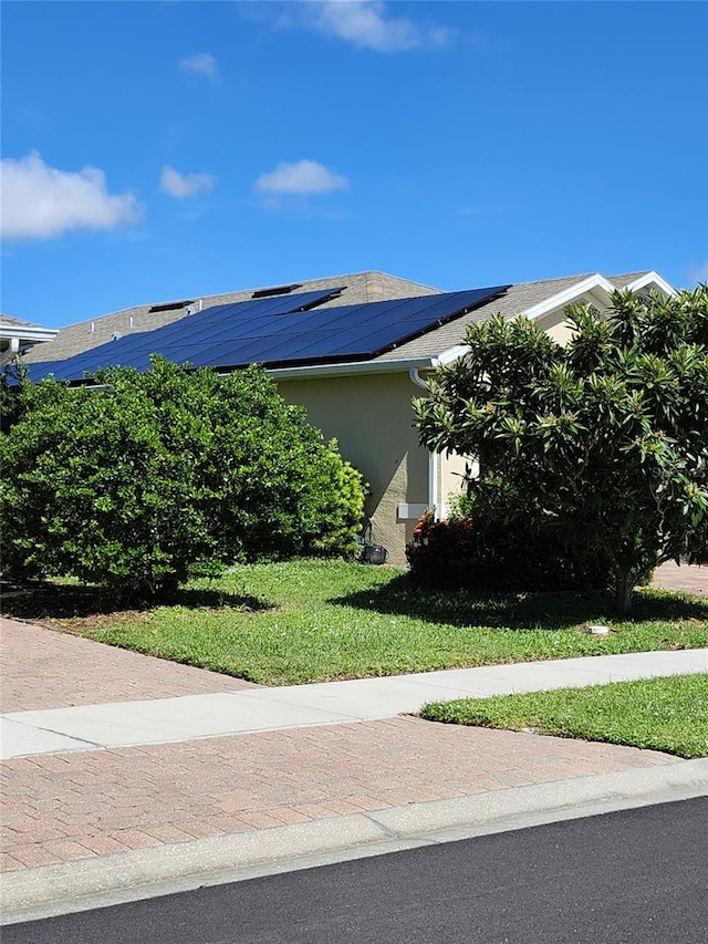 view of side of home featuring solar panels, a lawn, and stucco siding