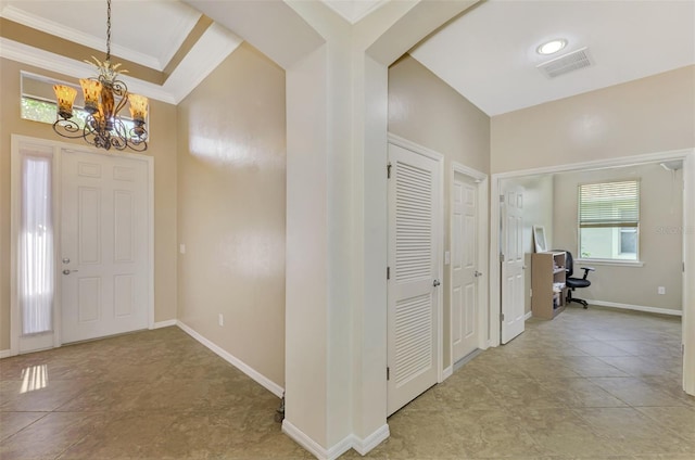 entryway featuring a notable chandelier, crown molding, visible vents, and baseboards