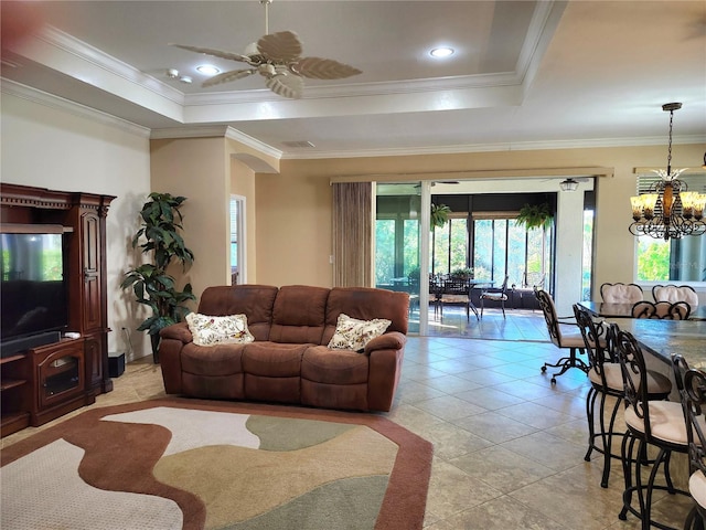 tiled living room featuring ceiling fan with notable chandelier, a raised ceiling, and ornamental molding