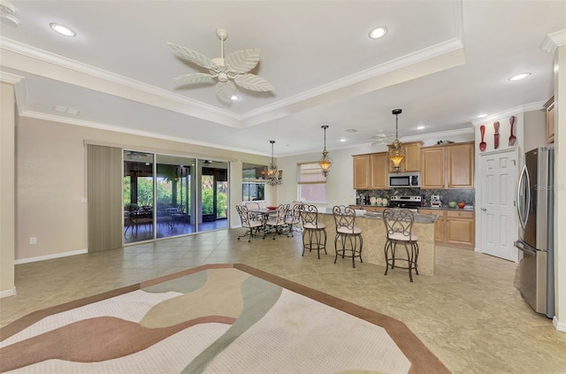 interior space with light tile patterned floors, ceiling fan with notable chandelier, a tray ceiling, and ornamental molding