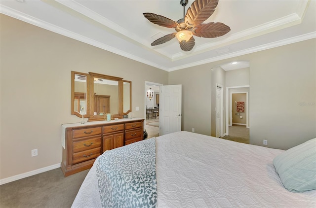 carpeted bedroom with a closet, a tray ceiling, ceiling fan, and crown molding