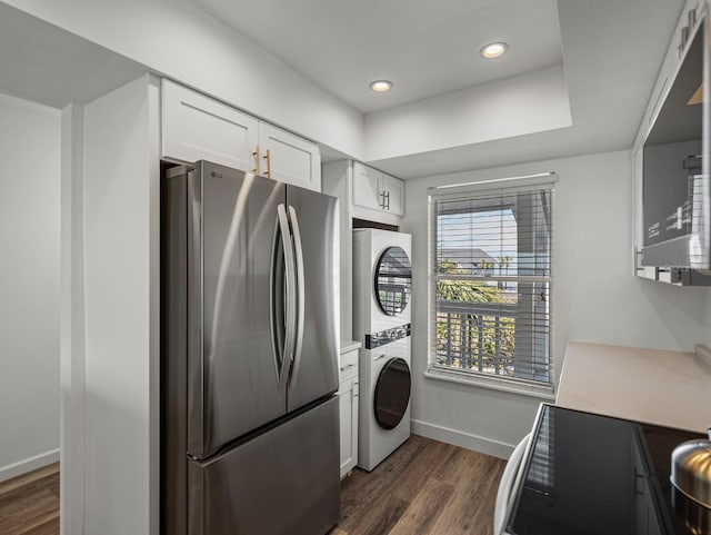 kitchen with stacked washer / dryer, white cabinetry, dark hardwood / wood-style flooring, and stainless steel refrigerator