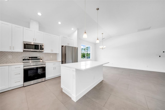 kitchen featuring tasteful backsplash, light tile patterned floors, stainless steel appliances, a kitchen island, and lofted ceiling