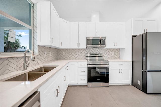 kitchen with stainless steel appliances, white cabinets, light countertops, and a sink