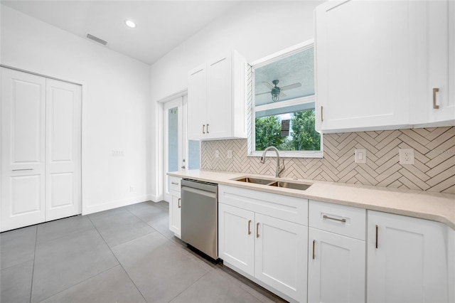 kitchen featuring tasteful backsplash, light countertops, white cabinets, a sink, and dishwasher