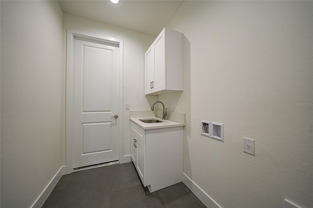 laundry room with cabinet space, baseboards, washer hookup, and a sink