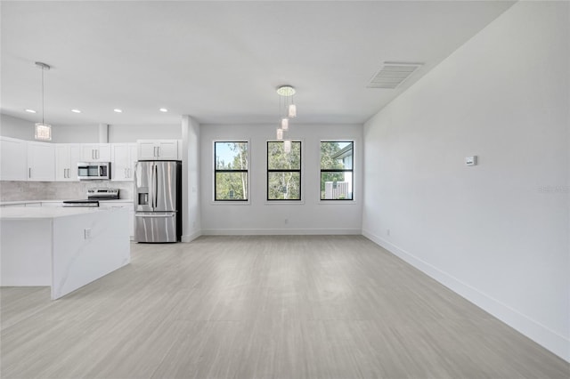 9262 Genesee St, Port Charlotte, FL 33981 - kitchen with stainless steel appliances, light countertops, white cabinetry, decorative backsplash, and decorative light fixtures