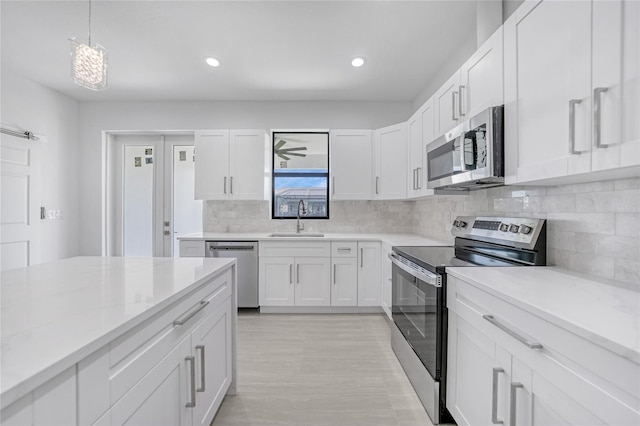 9262 Genesee St, Port Charlotte, FL 33981 - kitchen featuring stainless steel appliances, white cabinetry, decorative backsplash, recessed lighting, and hanging light fixtures