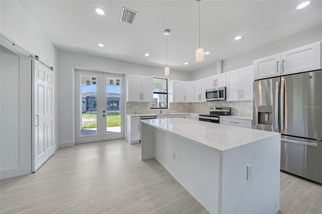 9262 Genesee St, Port Charlotte, FL 33981 - kitchen featuring appliances with stainless steel finishes, backsplash, a kitchen island, recessed lighting, and white cabinets