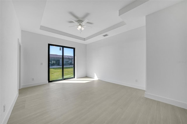 9262 Genesee St, Port Charlotte, FL 33981 - empty room with a ceiling fan, a tray ceiling, and light wood-type flooring