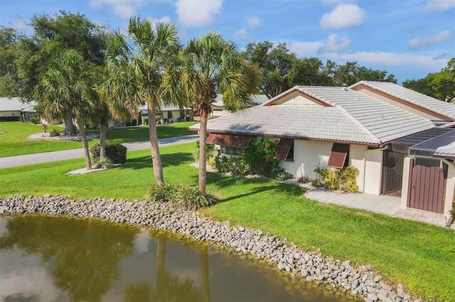 back of property with a water view and a yard