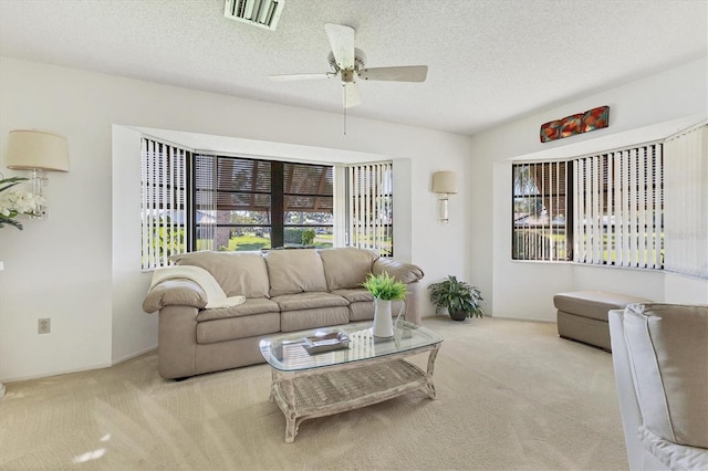 carpeted living room featuring ceiling fan and a textured ceiling