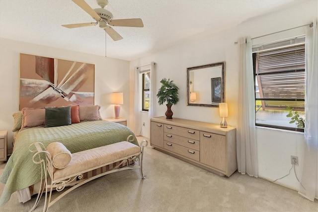 bedroom featuring multiple windows, ceiling fan, light colored carpet, and a textured ceiling