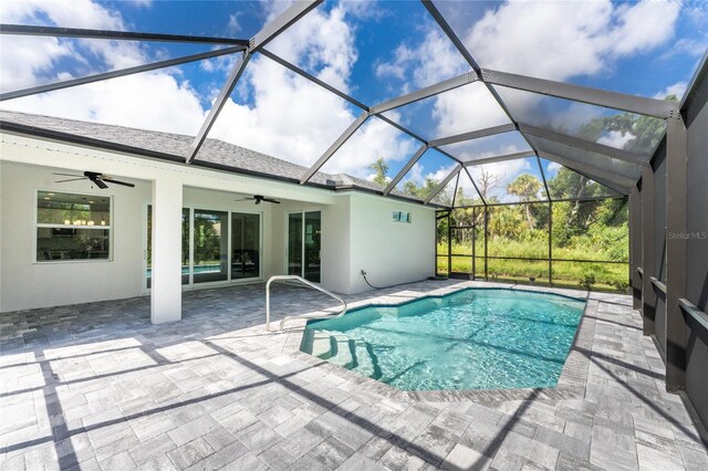 view of swimming pool with ceiling fan, a patio, and glass enclosure