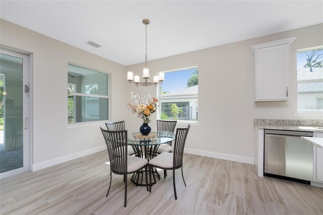 dining area with light hardwood / wood-style floors and a notable chandelier