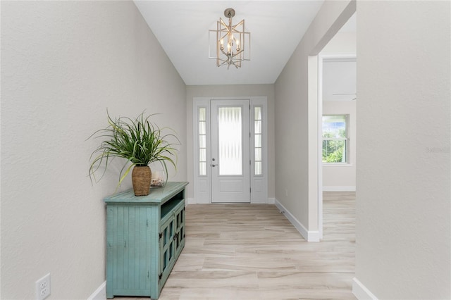 foyer with a healthy amount of sunlight, light hardwood / wood-style flooring, and a chandelier