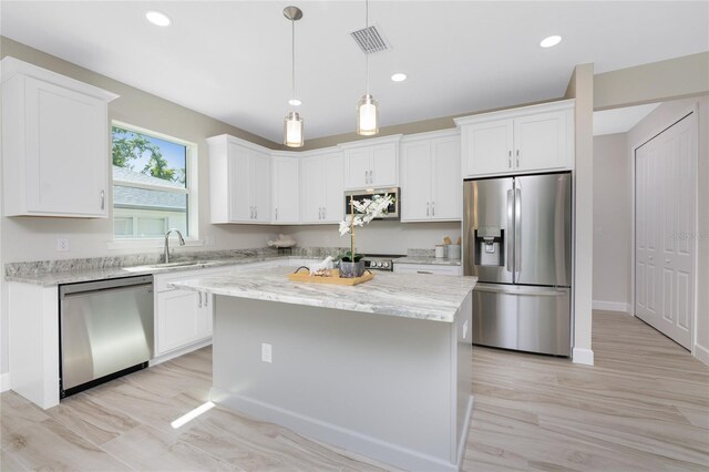 kitchen featuring a kitchen island, stainless steel appliances, light stone countertops, and white cabinetry