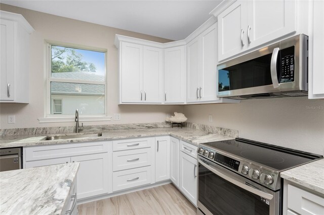 kitchen with light wood-type flooring, white cabinetry, stainless steel appliances, and sink