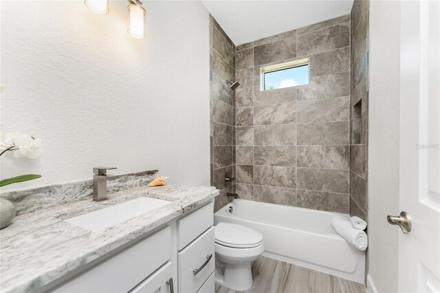 full bathroom with tiled shower / bath combo, vanity, toilet, and wood-type flooring