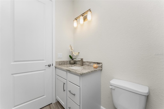 bathroom featuring toilet, hardwood / wood-style flooring, and vanity