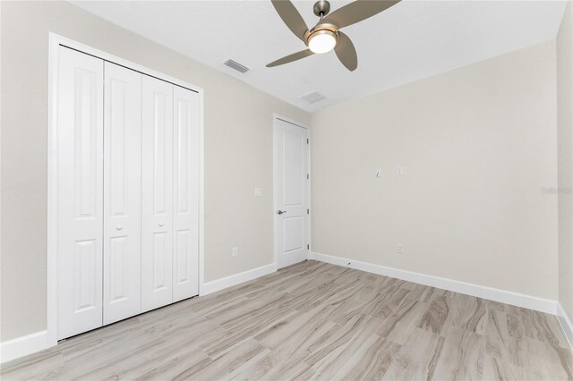 unfurnished bedroom featuring light hardwood / wood-style flooring, ceiling fan, and a closet