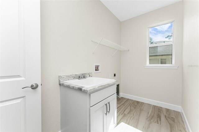 clothes washing area with hookup for a washing machine, cabinets, light hardwood / wood-style floors, sink, and hookup for an electric dryer