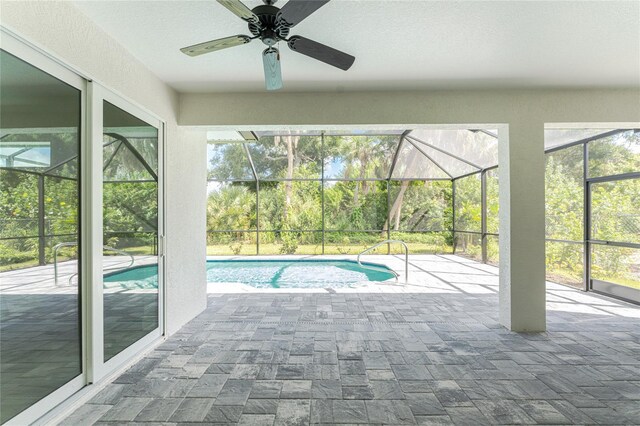 view of pool featuring glass enclosure, ceiling fan, and a patio