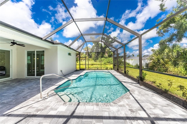 view of swimming pool with a lawn, glass enclosure, ceiling fan, and a patio