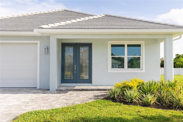 view of exterior entry featuring a garage and french doors