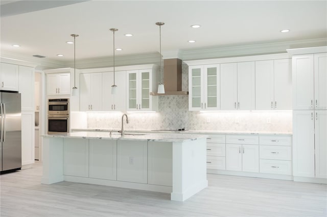 kitchen with stainless steel appliances, decorative backsplash, hanging light fixtures, a center island with sink, and wall chimney range hood